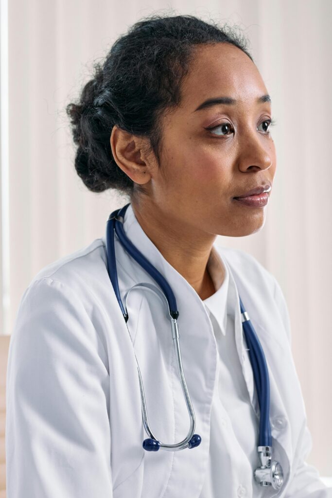 Close-up of a focused female doctor in a white coat with a stethoscope indoors.